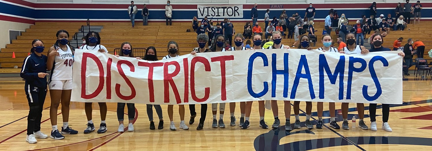 Tompkins players and coaches hold up the district championship banner sign following their 66-47 win over Seven Lakes on Jan. 22 that secured their second straight district title.