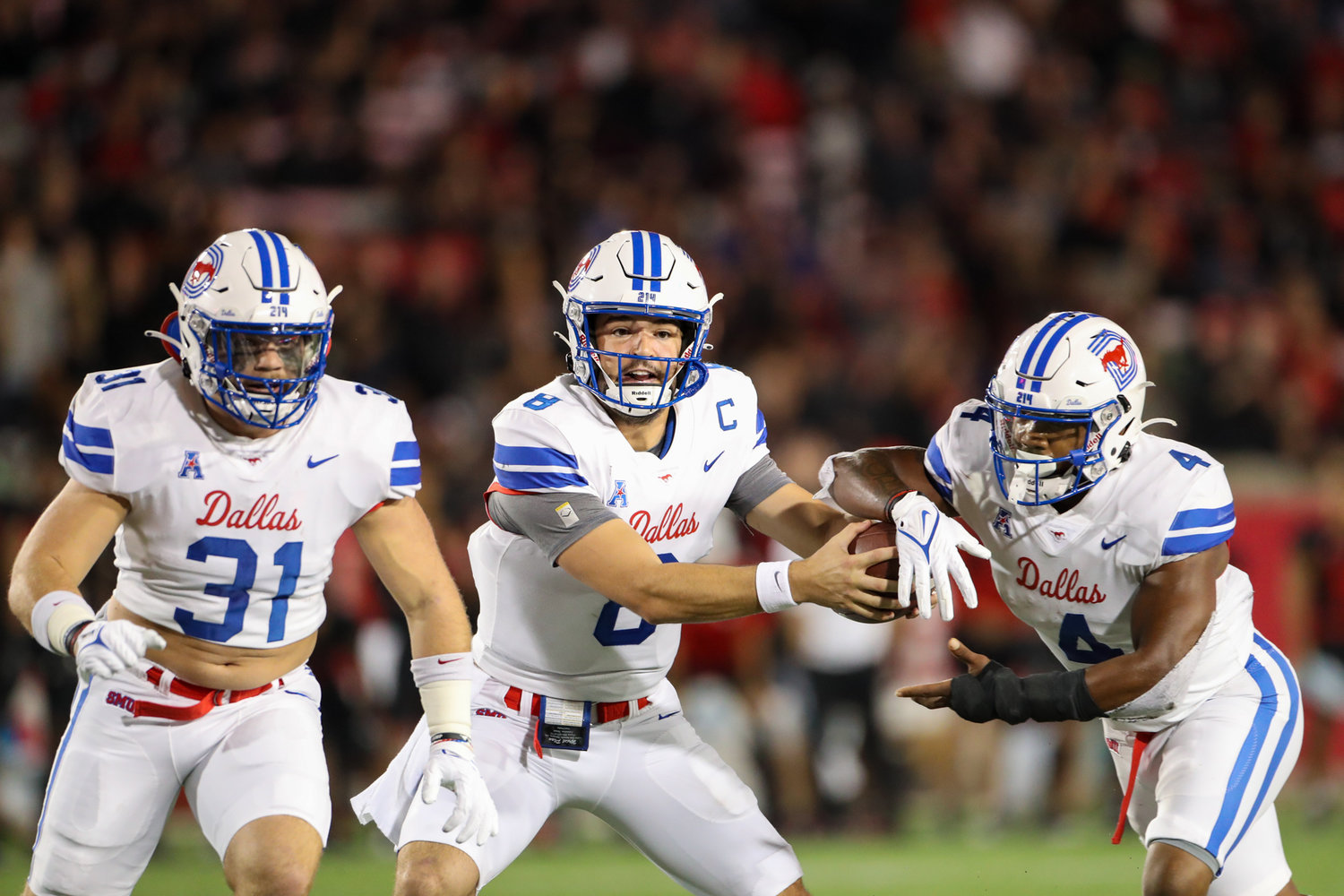 SMU Mustangs quarterback Tanner Mordecai (8) hands the ball off to running back Tre Siggers (4) as running back Tyler Lavine (31) prepares to block during an NCAA football game between Houston and SMU on October 30, 2021 in Houston, Texas.
