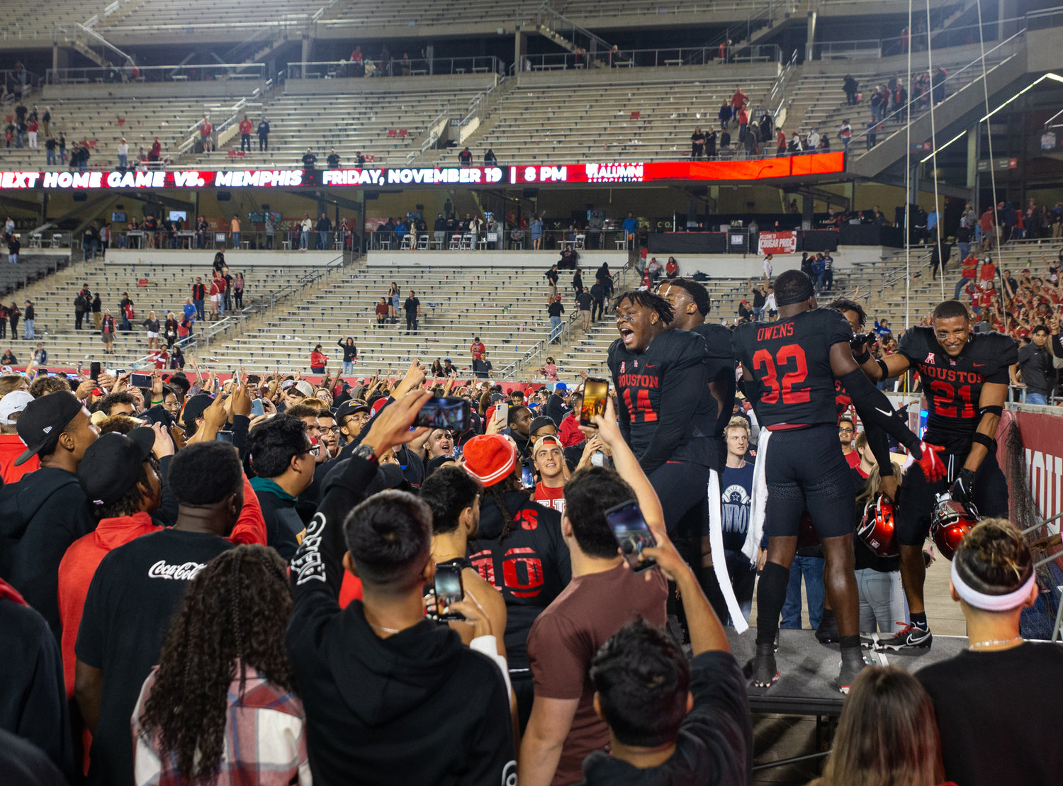 A group of Houston Cougars players celebrate on the field with fans after a 44-37 win over rival SMU in an NCAA football game on October 30, 2021 in Houston, Texas.
