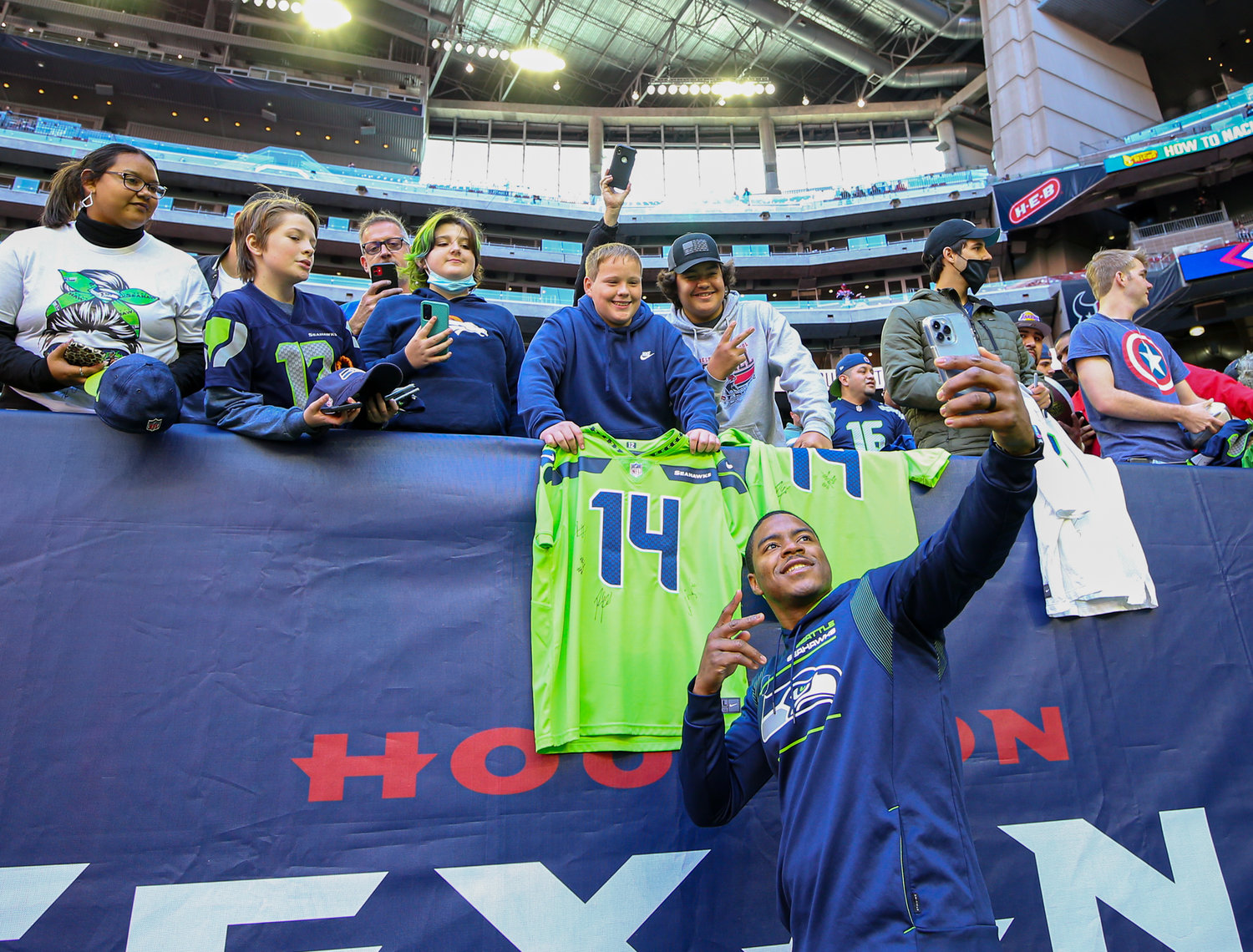 Seattle fans outnumber Texans fans in the stadium early early as wide receiver Freddie Swain (18) takes photos with Seahawks fans before the start of an NFL game on December 12, 2021 in Houston, Texas.