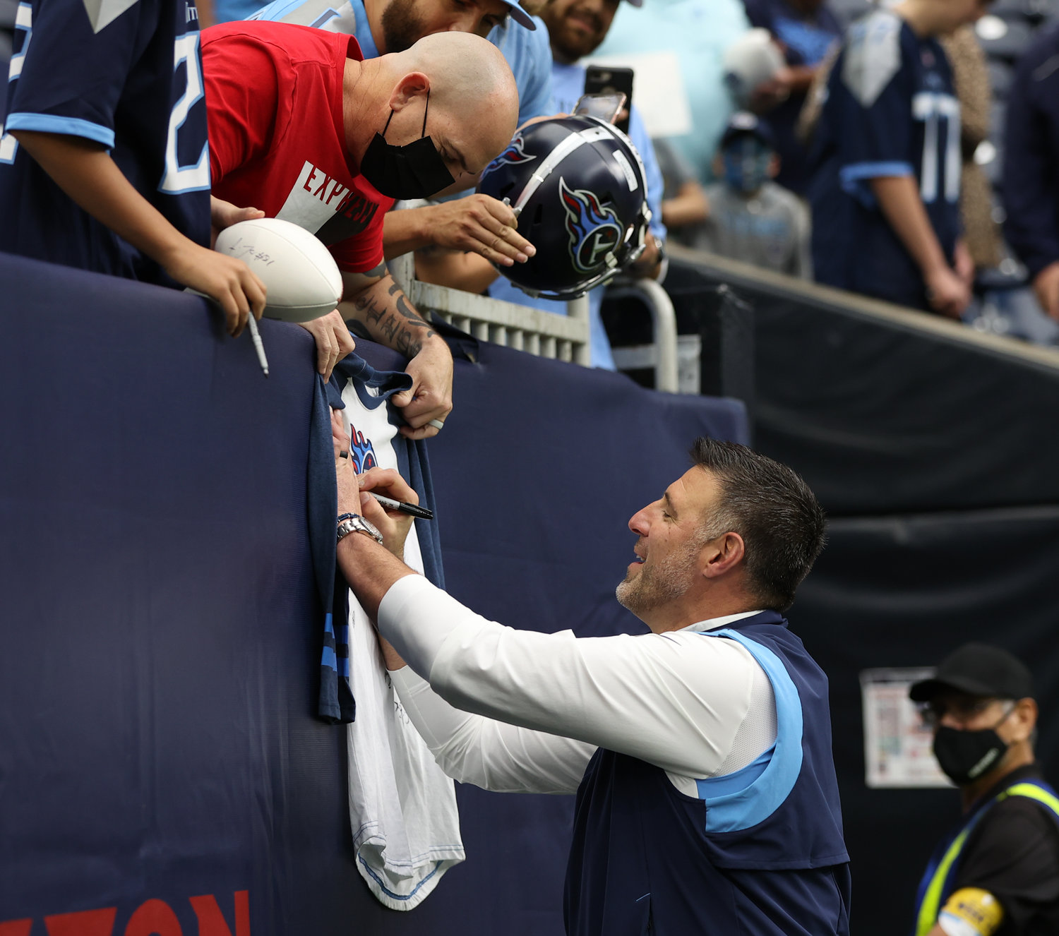 Tennessee Titans head coach Mike Vrabel autographs a shirt for a Titans fan before an NFL game between the Texans and the Titans on Jan. 9, 2022 in Houston, Texas. The Titans won, 28-25.
