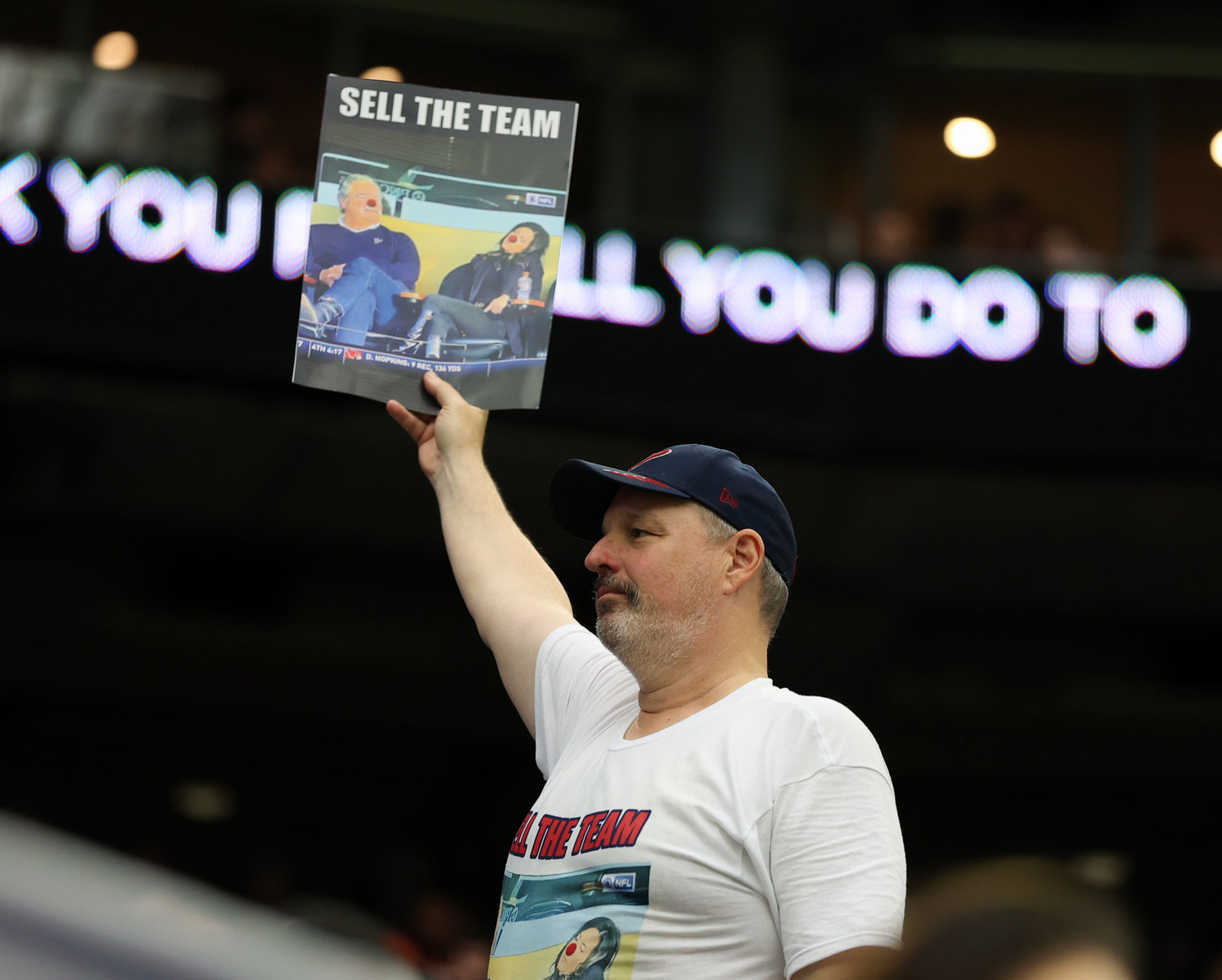 A Houston Texans fan holds up a sign saying “Sell the Team” with a photo of owner Cal McNair and wife Hannah during an NFL game between the Texans and the Titans on Jan. 9, 2022 in Houston, Texas. The Titans won, 28-25.