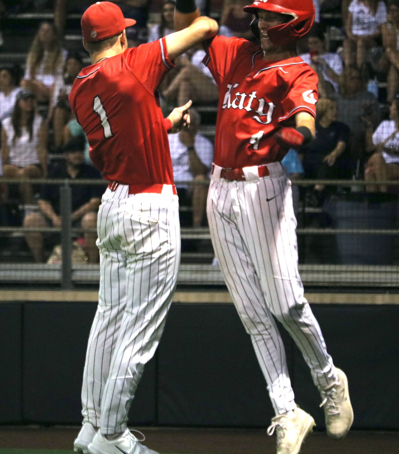 Andrew Hilton and Graham Laxton celebrate after Hilton scored a run during Friday's area round game between Katy and Cy-Fair at Langham Creek.