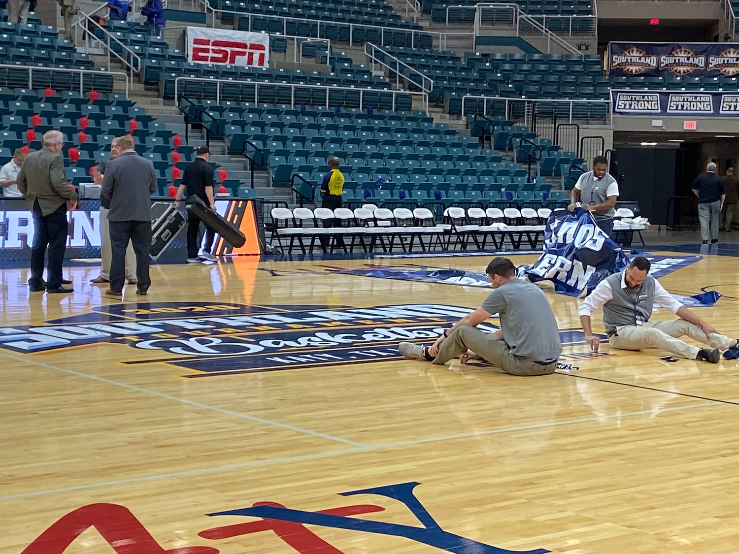 Southland Conference employees tear up floor logos promoting the tournament at the Merrell Center.