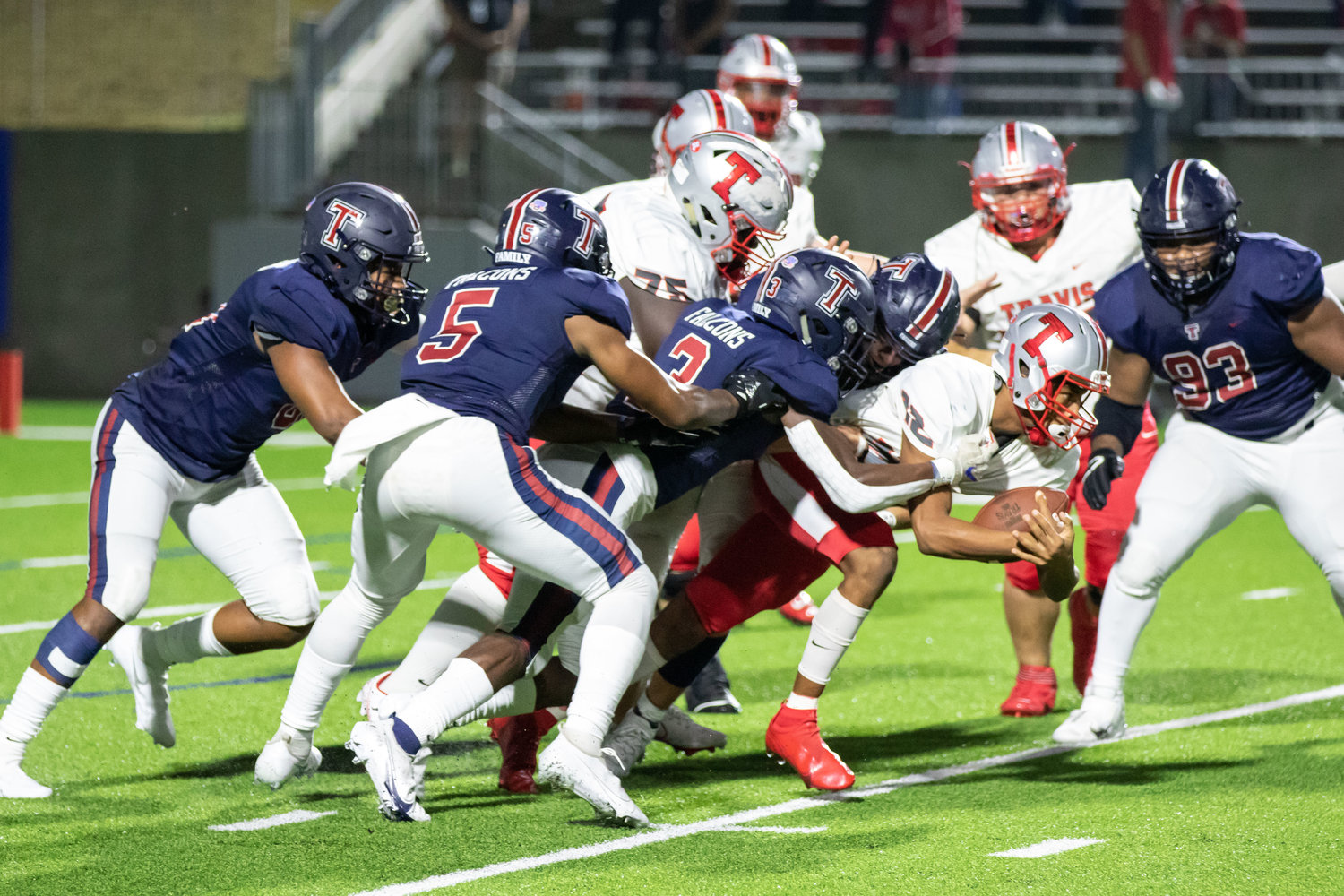 Tompkins defensive players swarm Travis quarterback Anthony Njoku during the Falcons' 42-10 Class 6A Division I bi-district playoff win over Fort Bend Travis on Dec. 11 at Legacy Stadium.
