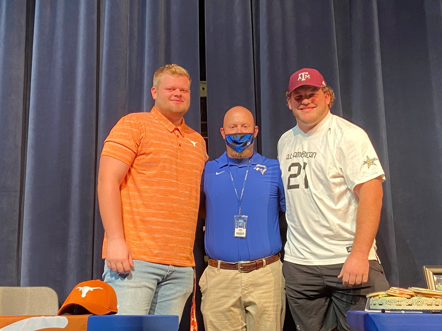 Taylor High senior offensive tackle and Texas signee Hayden Conner, left, and senior offensive guard and Texas A&M signee Bryce Foster, right, pose for a photo with offensive line coach Travis Sharp during their signing ceremony Friday at the performing arts center at Taylor High.