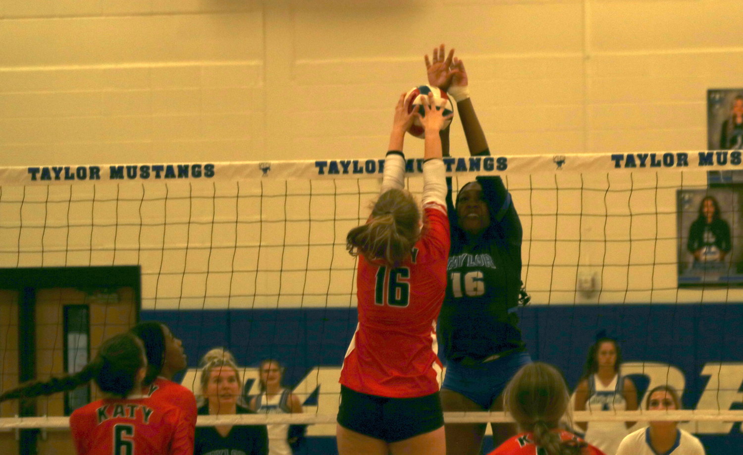 Maddie Waak tries to tip a ball over the net while Bria Dixon tries to block it during a District 19-6A match between Katy and Taylor at the Taylor gym.