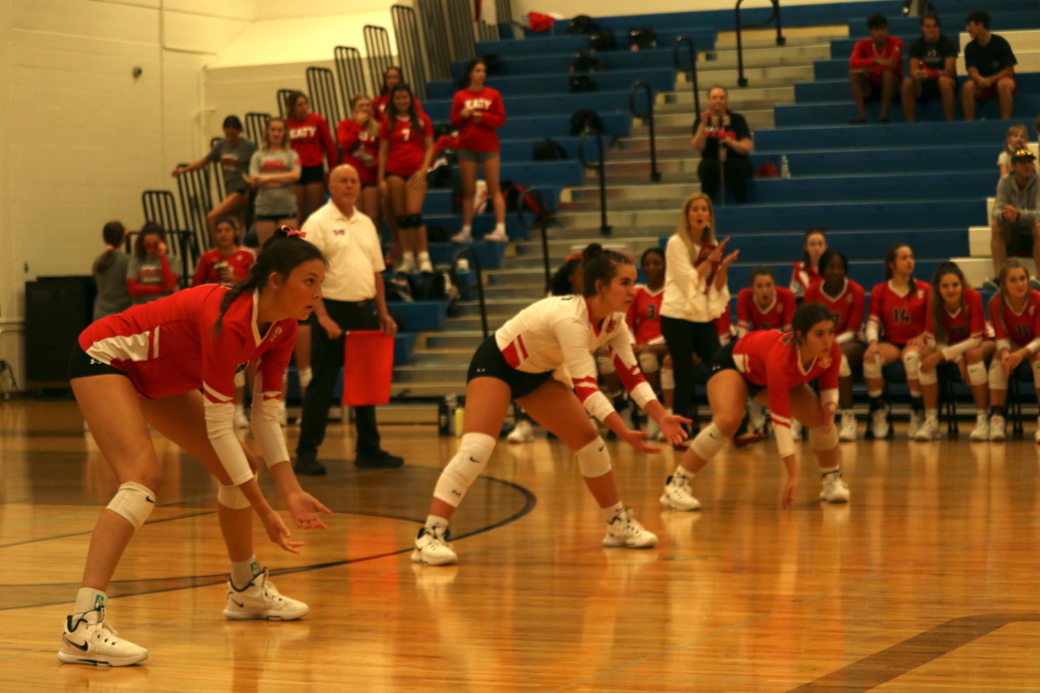 The back line of Katy players prepares for a serve as head coach Karen Paxton tells the team instructions during a District 19-6A match between Katy and Taylor at the Taylor gym.