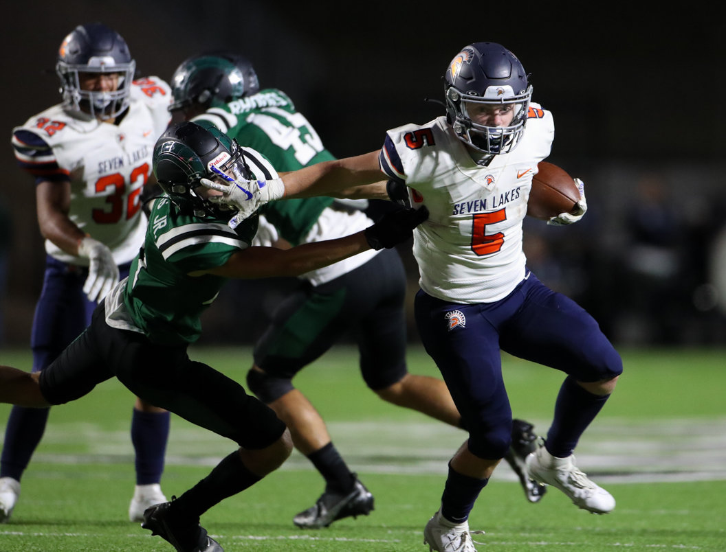 Seven Lakes Spartans running back Barrett Hudson (5) delivers a stiff arm to Mayde Creek Rams defensive back Ryan Waters (31) on a 27-yard touchdown run during a high school football game between Mayde Creek and Seven Lakes on October 29, 2021 in Katy, Texas. Seven Lakes won, 50-10.