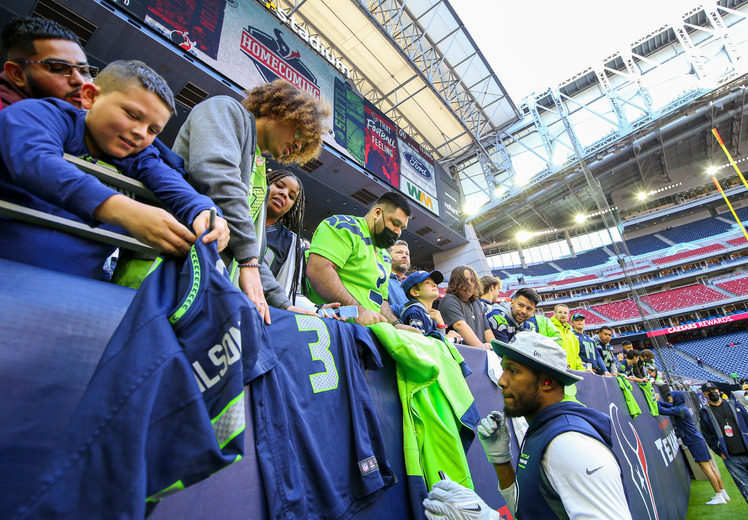 Seattle fans outnumber Texans fans in the stadium early as linebacker Carlos Dunlap II (8) signs souvenirs for Seahawks fans before the start of an NFL game on December 12, 2021 in Houston, Texas.