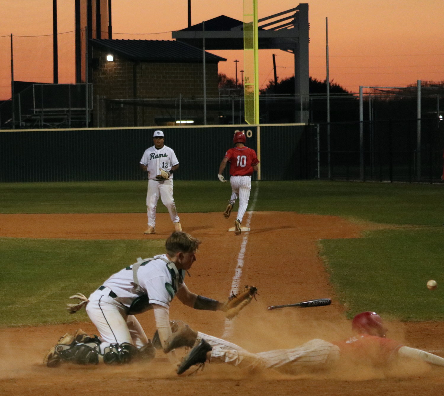 A ball gets away from Hayden Fullem as a Katy runner scores during Tuesday’s game between Katy and Mayde Creek at the Mayde Creek baseball field.