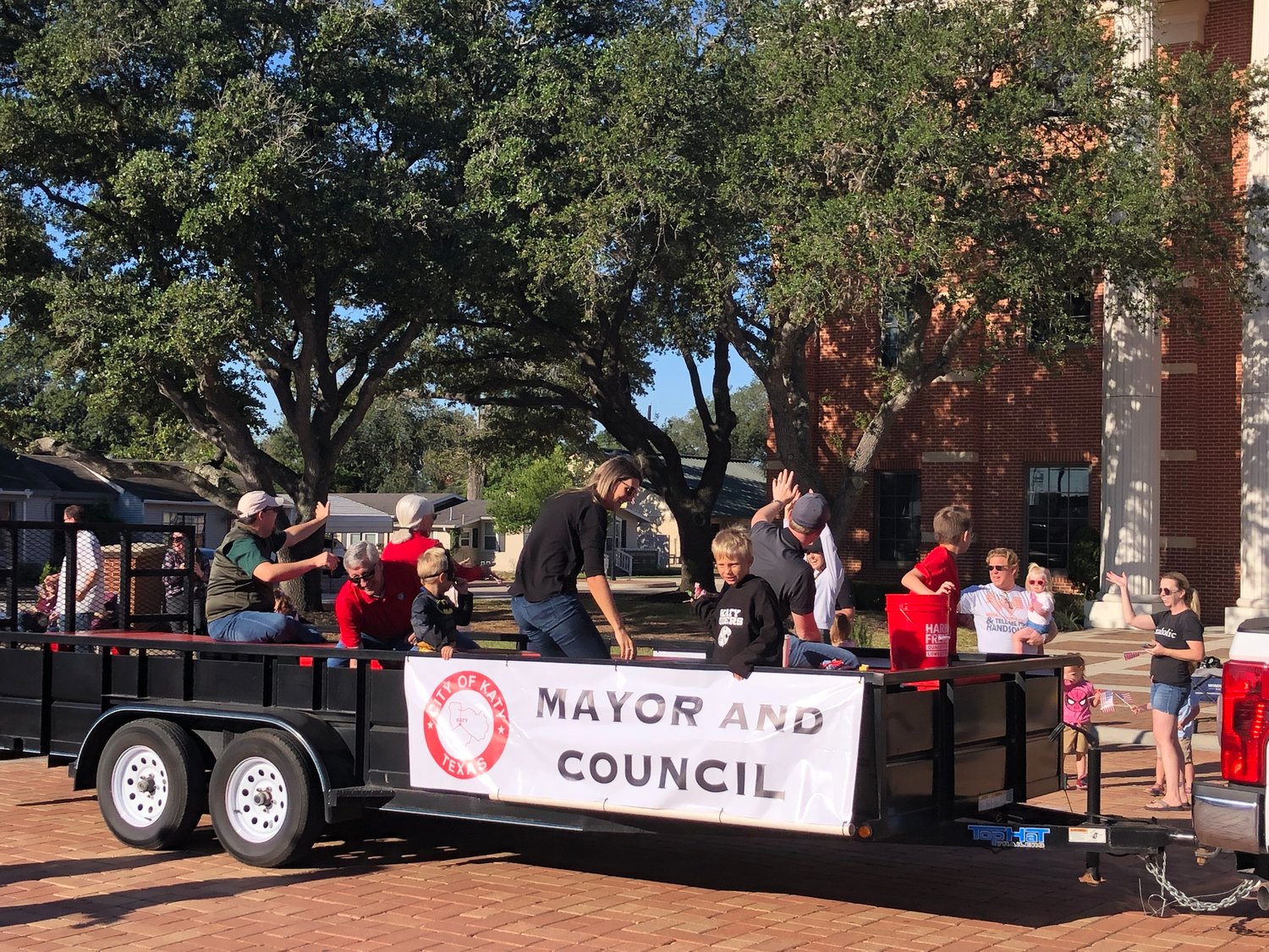 Mayor Dusty Thiele, in red shirt at left, is getting some candy to toss to the crowd, while other Katy City Council members toss candy to onlookers.