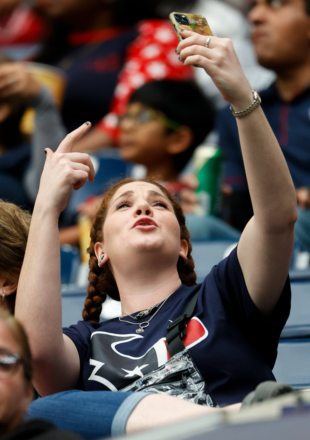 A Texans fan on her phone during an NFL game between the Houston Texans and the Jacksonville Jaguars on Jan. 1, 2023 in Houston. The Jaguars won, 31-3.