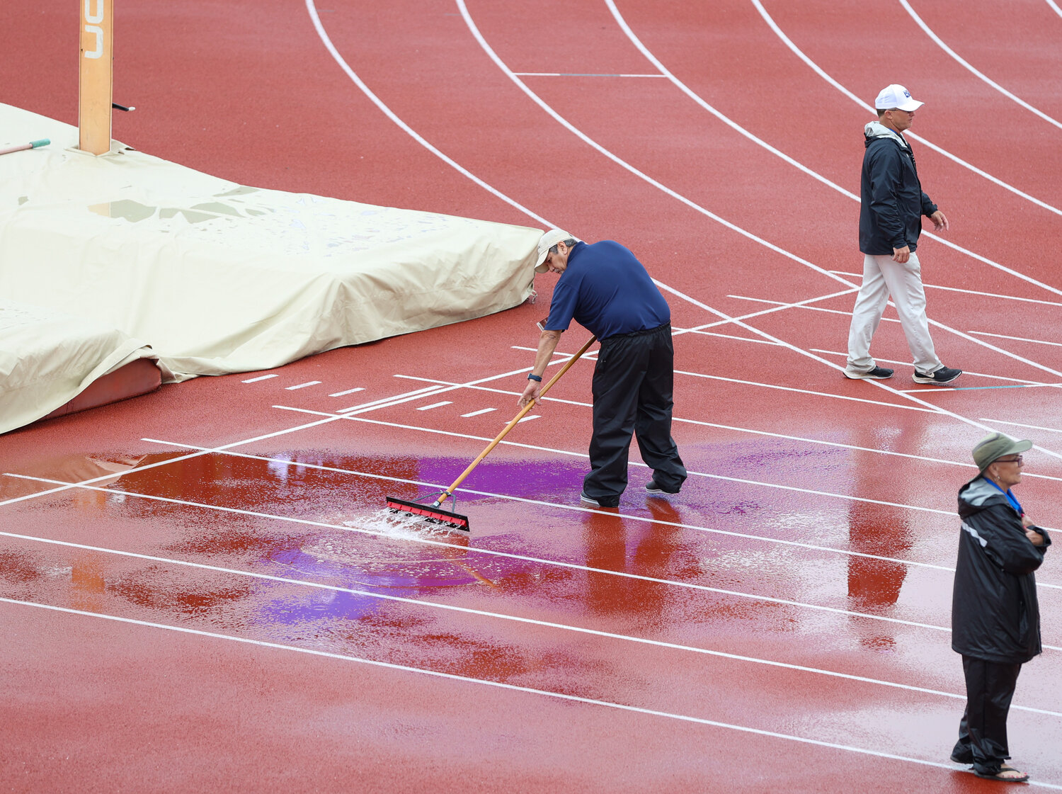 A volunteer clears the approach area in front of the pole vault venue of standing water following a rain delay during the UIL State Track and Field Meet on Saturday, May 13, 2023 in Austin.