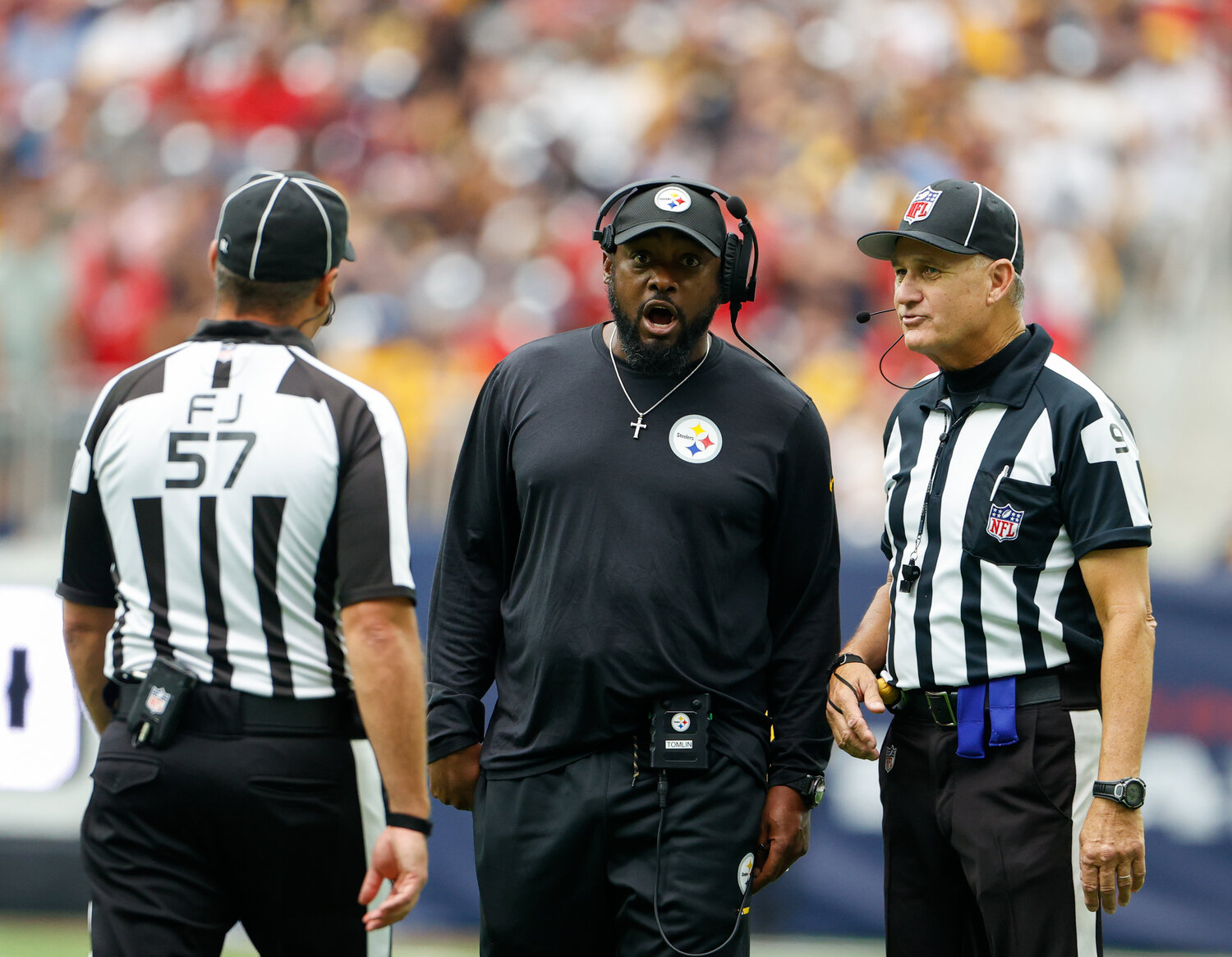 Steelers head coach Mike Tomlin discusses a call with field judge Joe Blubaugh (57) and line judge Mark Perlman (9) during an NFL game between the Houston Texans and the Pittsburgh Steelers on October 1, 2023 in Houston.